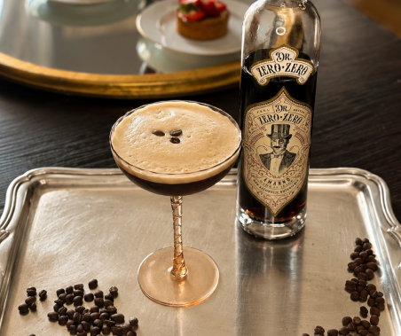 Cocktail in a glass with a bottle of Dr. Zero-Zero on a tray with chocolate chips.