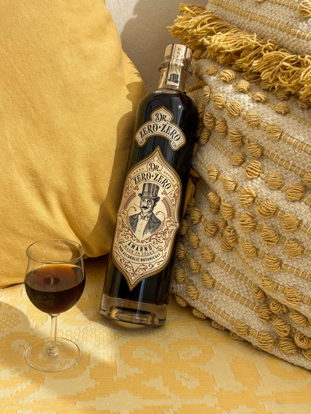 Bottle of J.R. Ely Whiskey with a glass on a textured yellow surface